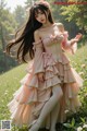 A woman in a pink dress standing in a field of flowers.