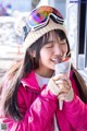 A woman in a pink jacket and hat eating an ice cream cone.