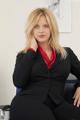 A woman in a business suit sitting on a chair.