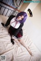 A woman with purple hair sitting on a bed.