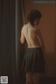 A woman standing in front of a curtain with her back to the camera.