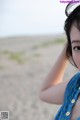 A woman in a blue dress standing on a beach.