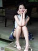 A woman sitting on a wooden bench with her legs crossed.