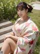 A woman in a kimono sitting on a wooden bench.