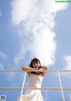 A woman in a white dress standing on a railing.