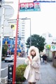 A woman standing on a sidewalk talking on a cell phone.