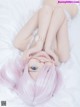 A woman with pink hair laying on a bed.